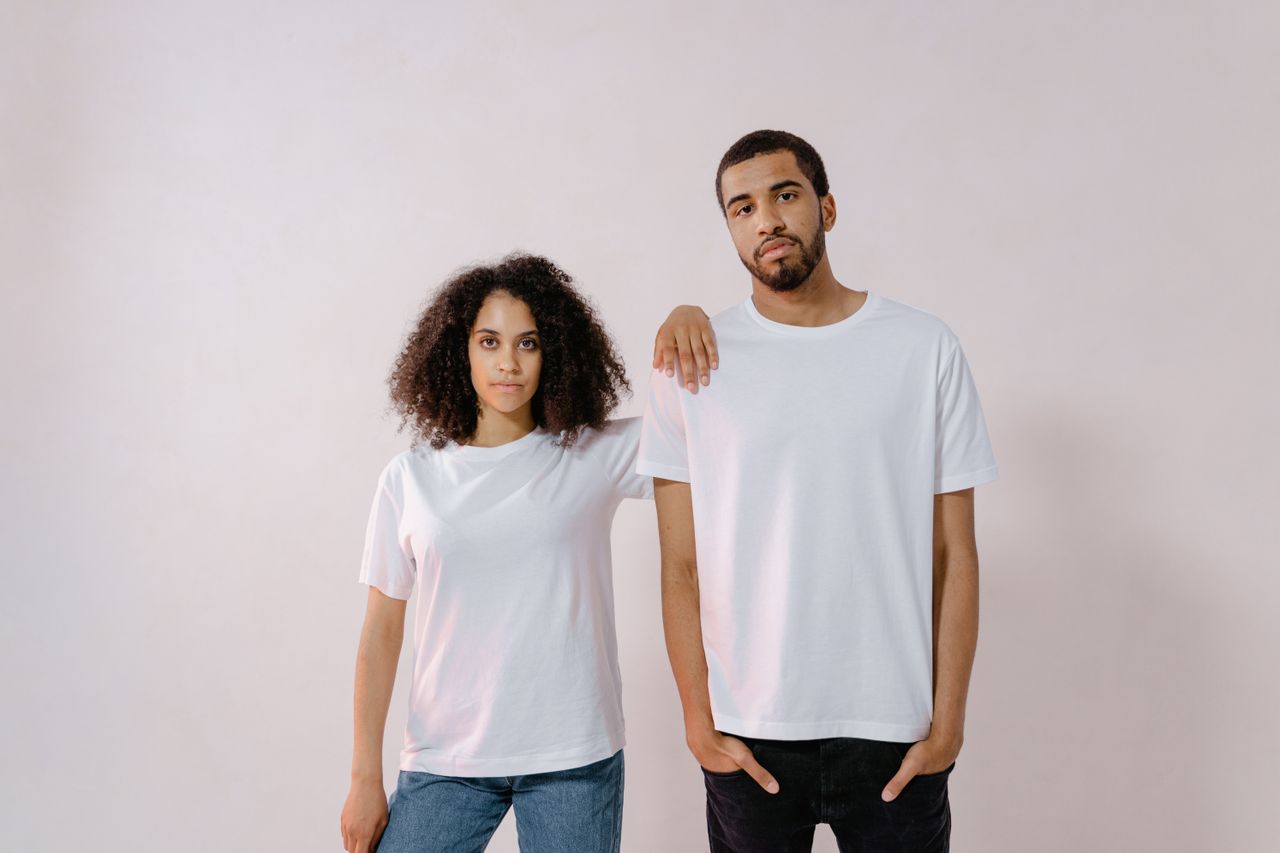 A young man and woman in casual white T-shirts, standing confidently for a fashion photoshoot.